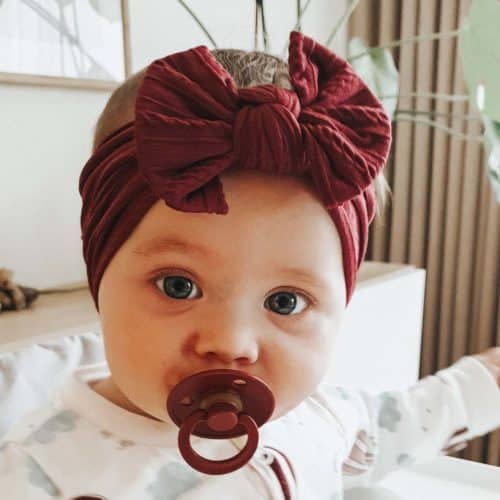 Bebis med vinrött huvudband och napp